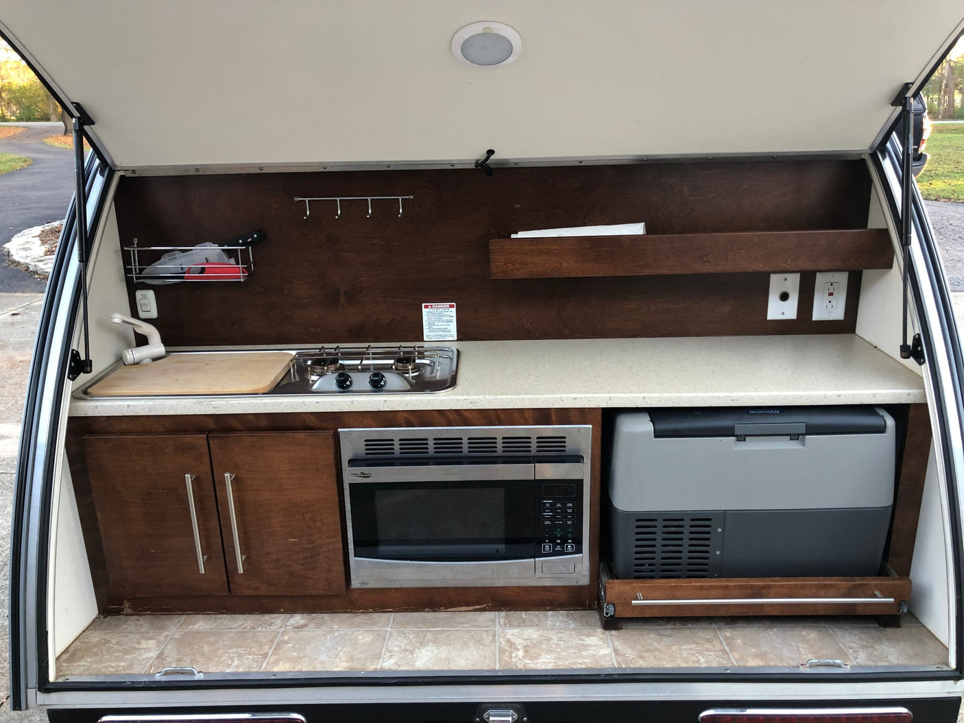 Teardrop RV rental's rear galley: Complete outdoor kitchen with sink, stove, microwave, fridge, and storage.