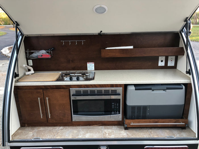 Teardrop RV rental's rear galley: Complete outdoor kitchen with sink, stove, microwave, fridge, and storage.