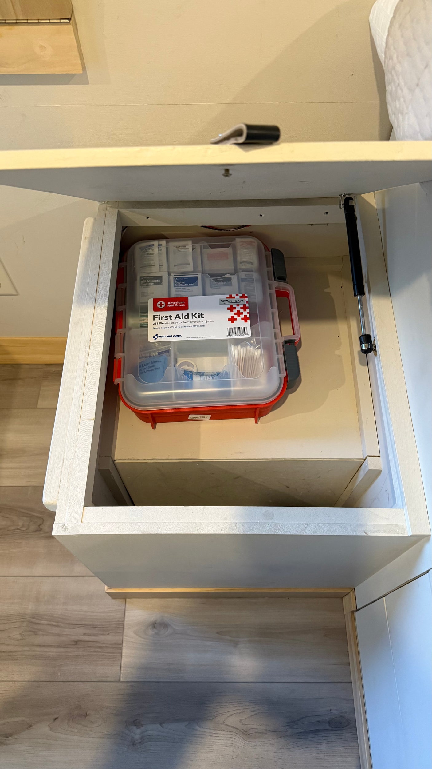 An open storage cabinet in an RV rental, showing a well-stocked American Red Cross First Aid Kit, essential for safe travels.