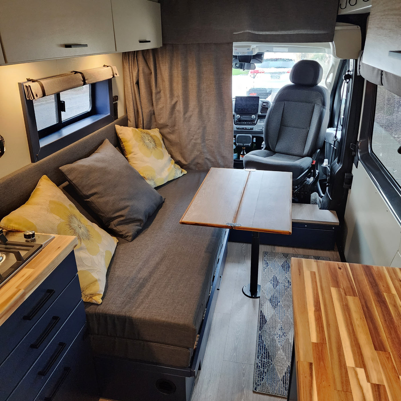 This RV rental features a versatile living space with a long bench seat, fold-out table, and kitchen.