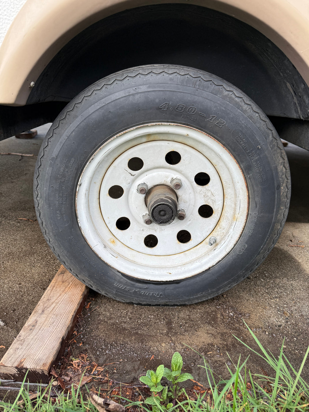 A 4.80-12 trailer tire, marked 'FOR TRAILER USE ONLY', on a white wheel, often found with an RV rental, resting on a wooden block. — photo 16