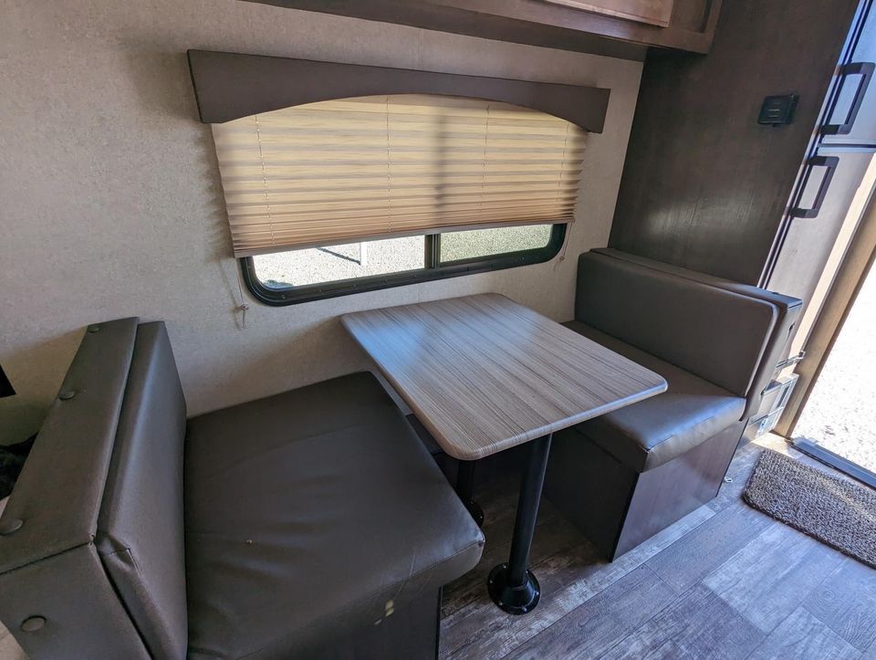 and an adjacent bed.|Compact RV rental interior: features an unused bed in plastic