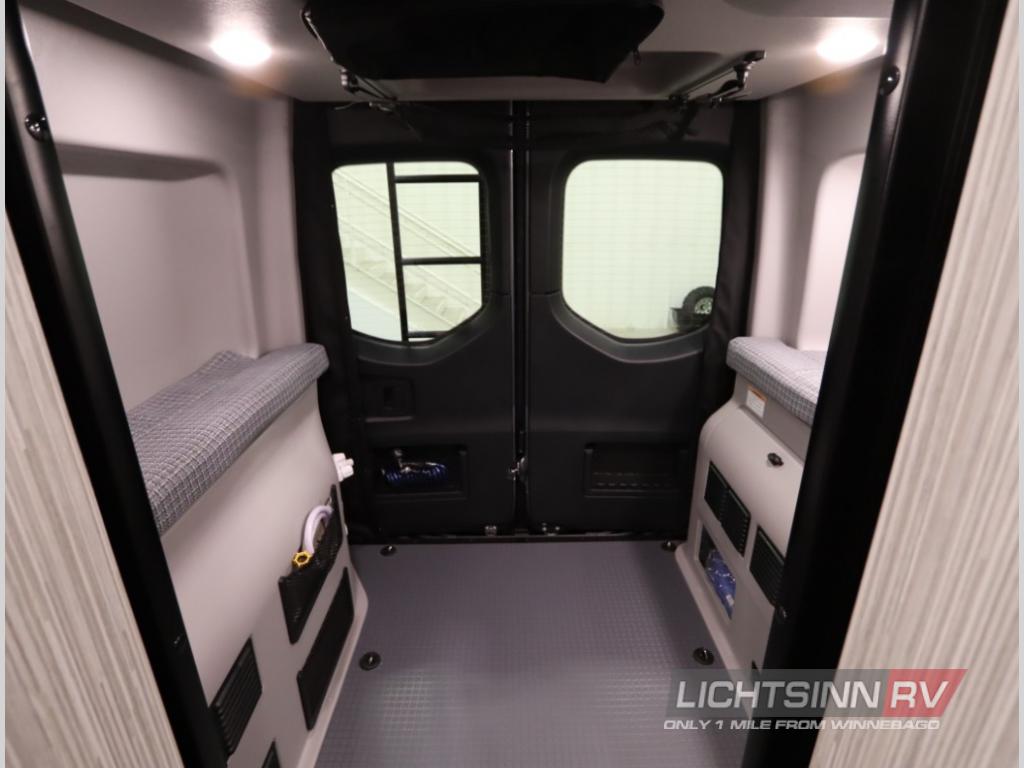 Spacious RV rental interior viewed from front, showing twin sleeping benches, rear doors, and organized storage for camper adventures.