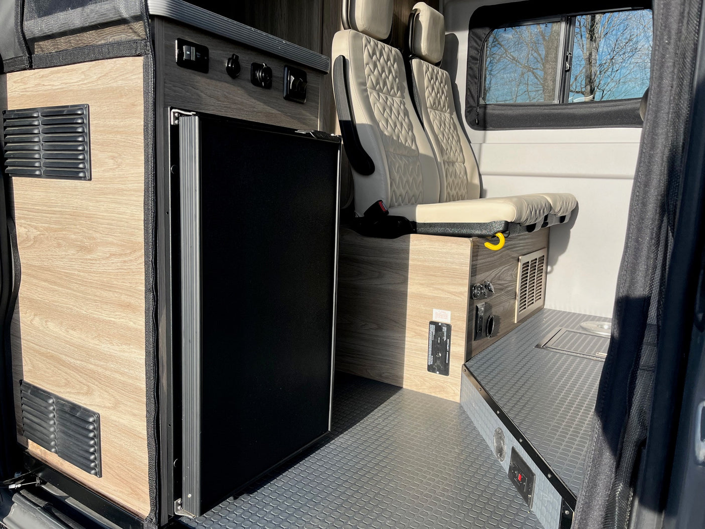 RV rental interior featuring a compact kitchenette with a built-in fridge, cozy seating, and durable flooring for travel.