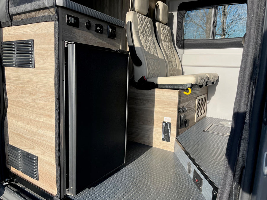 RV rental interior featuring a compact kitchenette with a built-in fridge, cozy seating, and durable flooring for travel.