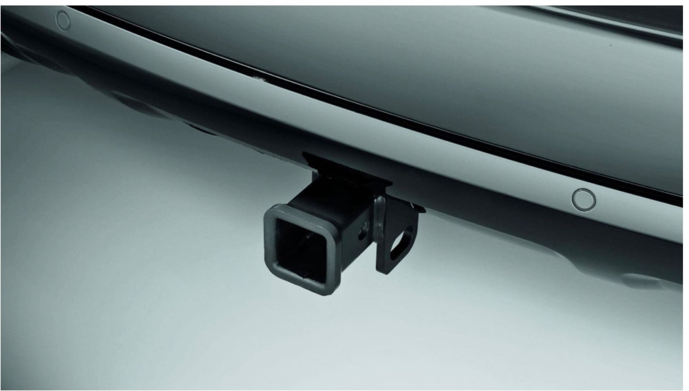 A dark vehicle's rear bumper features a square trailer hitch receiver, ideal for RV rental and towing. Parking sensors are also present.