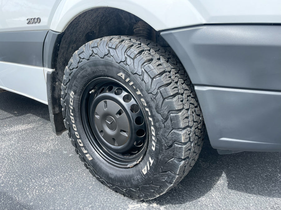 White RV rental van features rugged BFGoodrich All-Terrain T/A K02 tires on black steel wheels, ready for adventure.
