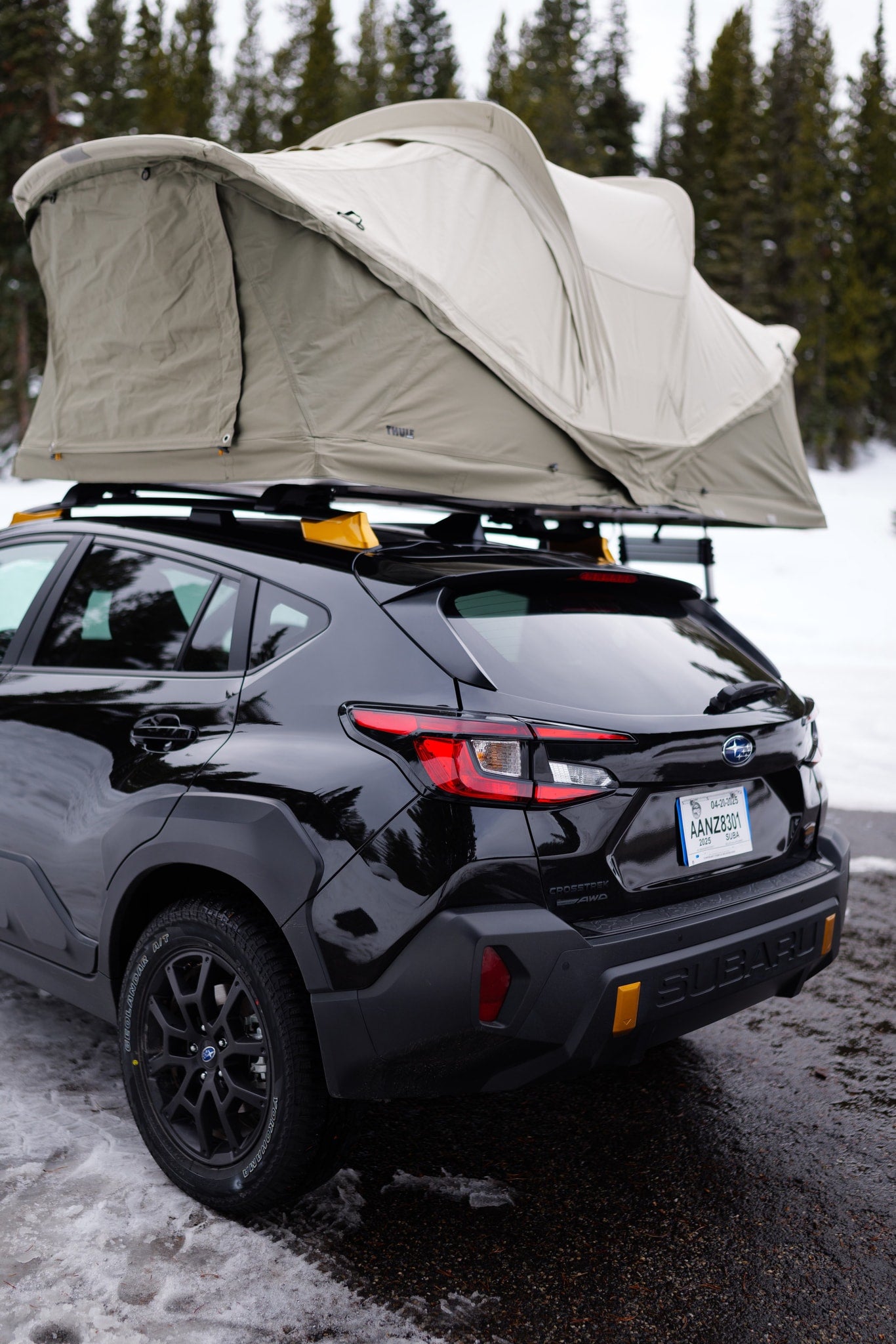 Black Subaru Crosstrek with a Thule rooftop tent, parked in a snowy forest, an agile option for an RV rental adventure. — photo 3