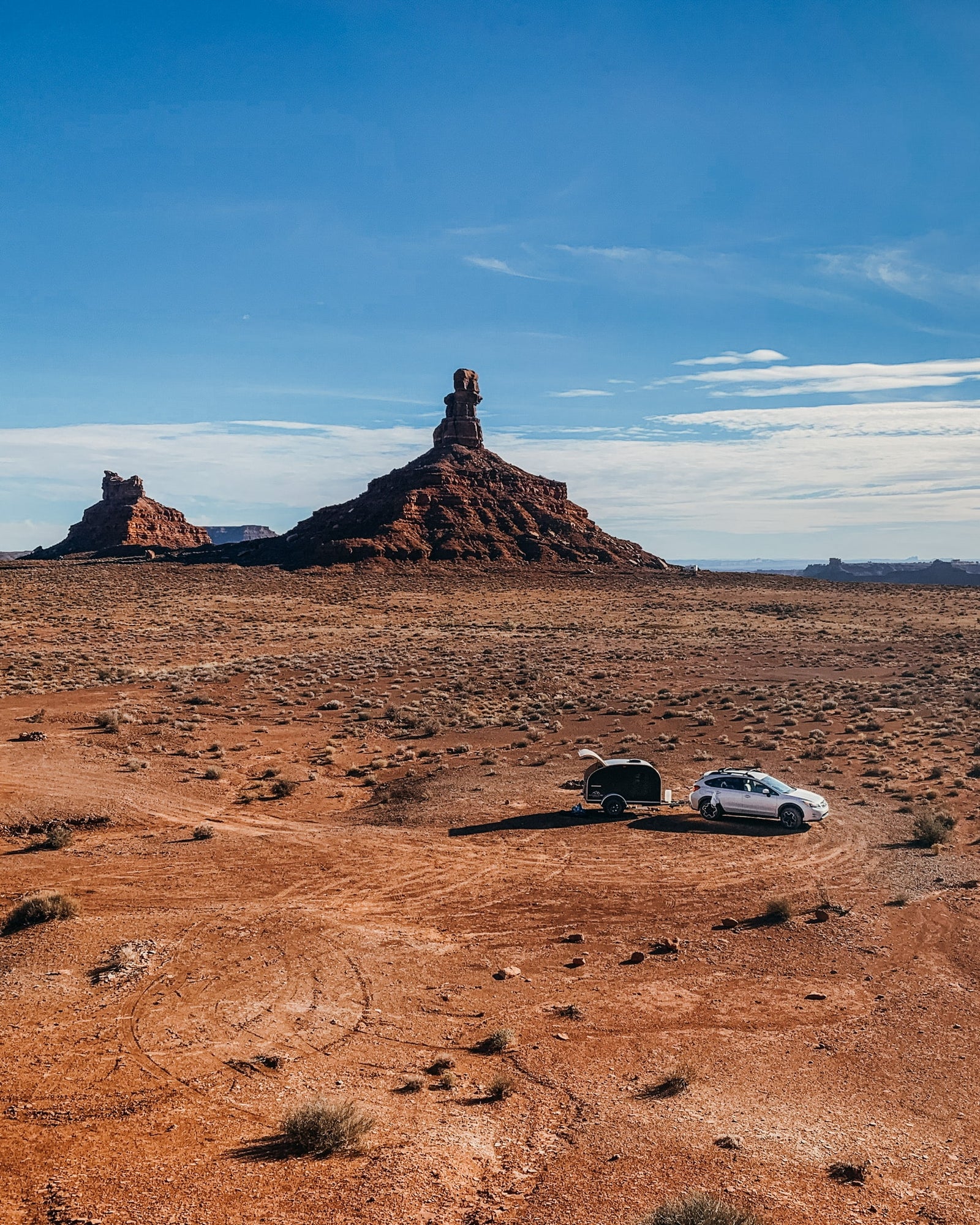 ready for your next RV rental.|RV rental teardrop trailer in a vast red desert with impressive rock formations under a clear blue sky. Ideal for off-grid camping.|Cozy black teardrop camper