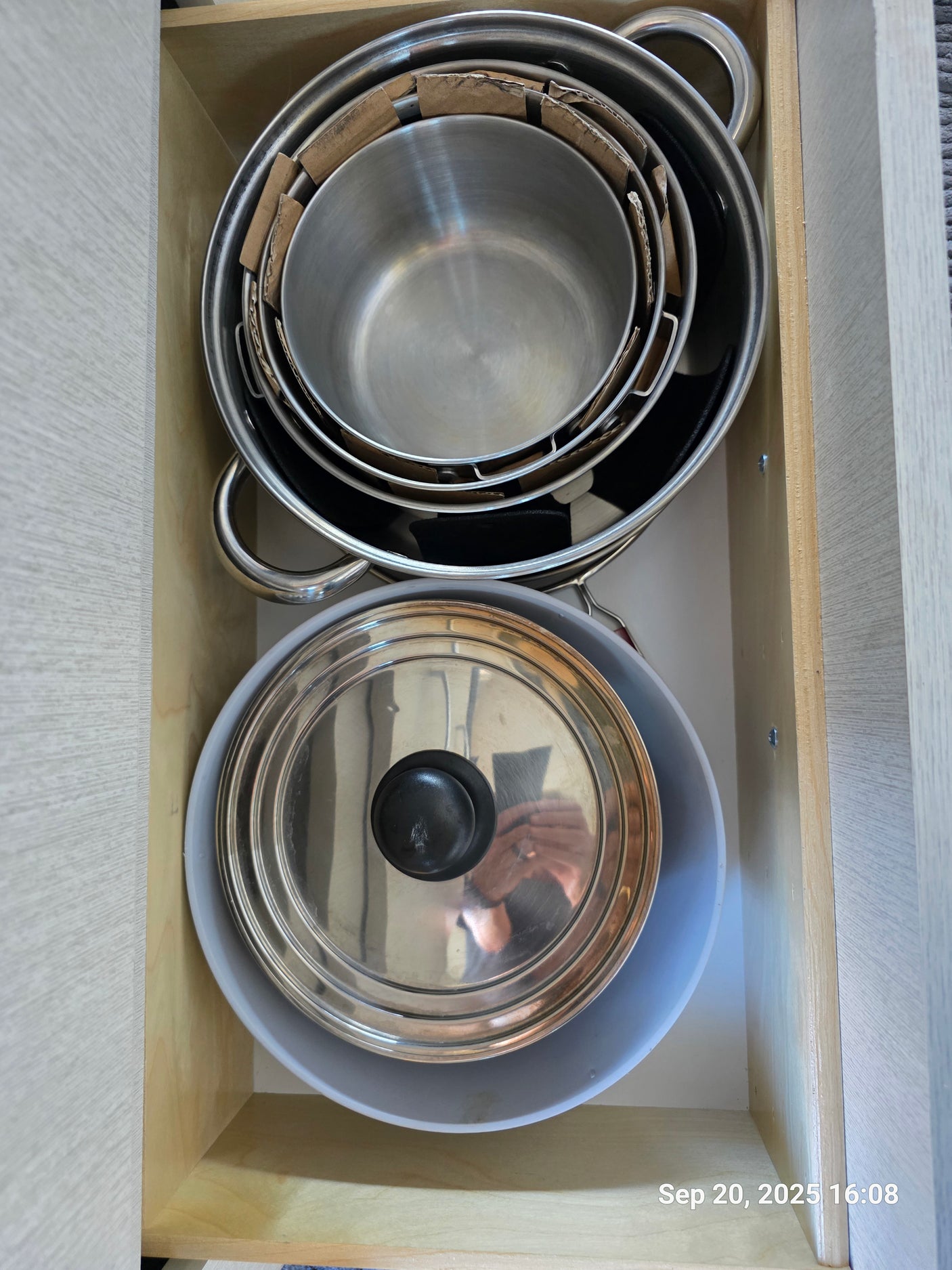 Organized kitchen drawer in an RV rental with stacked pots, pans, and a lid for easy access.