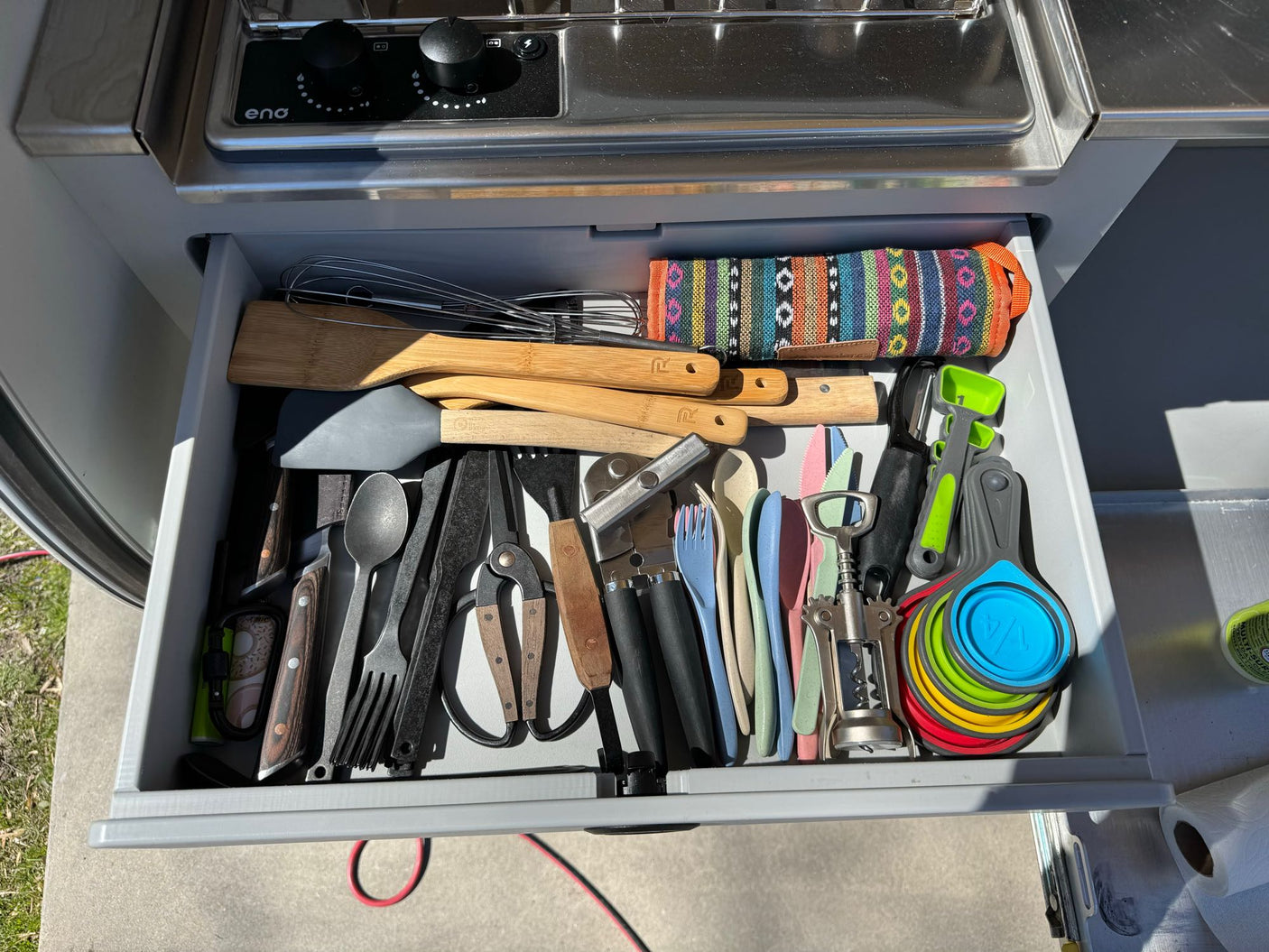 An RV rental kitchen drawer, neatly filled with diverse cooking utensils: spatulas, whisks, knives, measuring cups, and more.