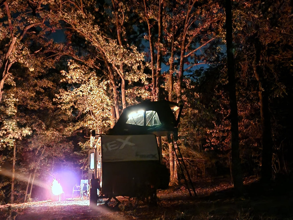 is towing an Ibex off-road camper trailer—a rugged RV rental setup.|An Ibex travel trailer RV rental with an open rooftop tent and ladder is parked in a sunny — photo 4