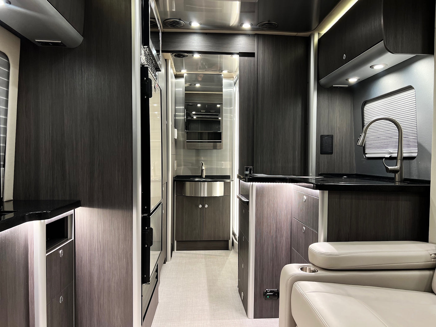 Inside a sleek rv rental: modern kitchen, compact bathroom vanity, and comfy seating in a contemporary design.
