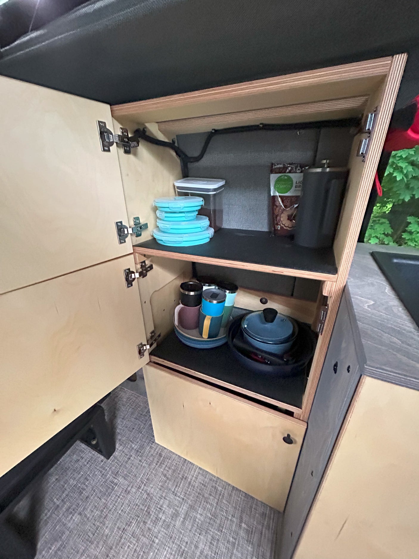 RV rental kitchen storage: open cabinets reveal organized dishes, mugs, and food prep items.