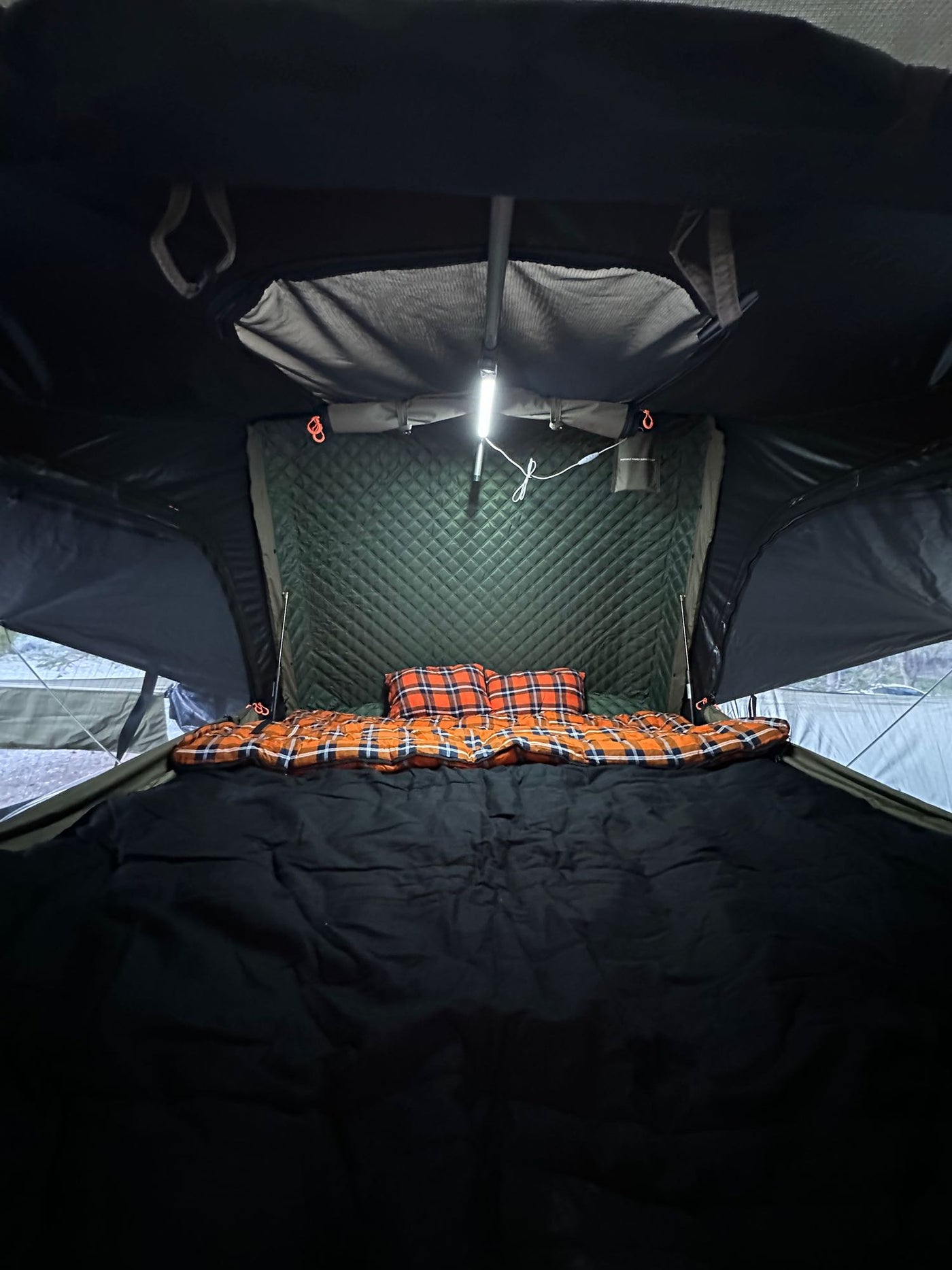 Inside a comfy rooftop tent bed with plaid bedding & bright light. Ideal for rv rental camping. — photo 19