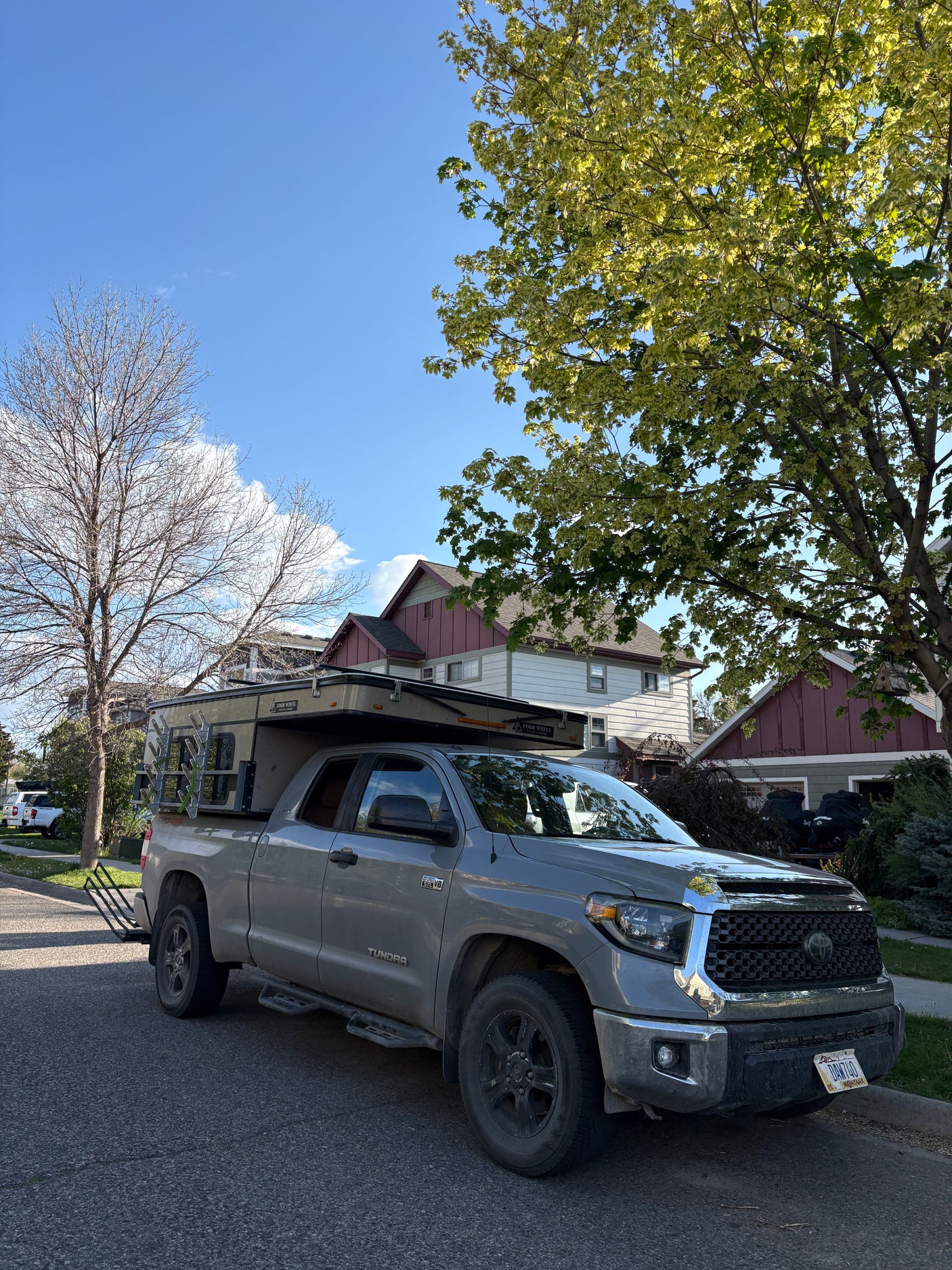 Grey Toyota Tundra with a Four Wheel Pop-up Camper, an RV setup, parked on a residential street. Ideal for an RV rental adventure.