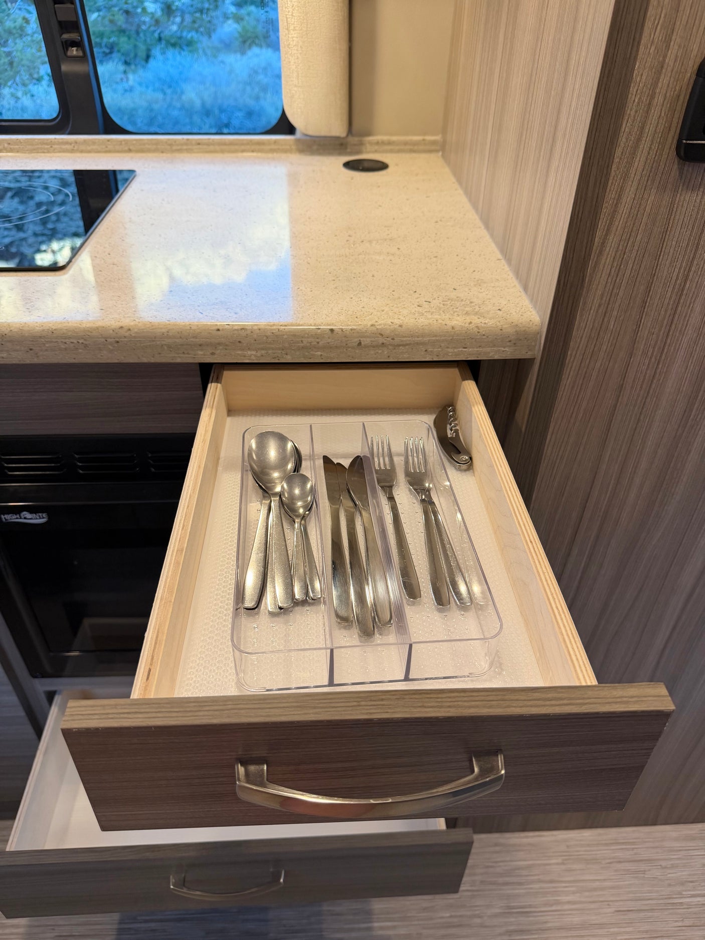 This RV rental kitchen drawer features an organized set of silverware, including spoons, knives, forks, and a corkscrew.