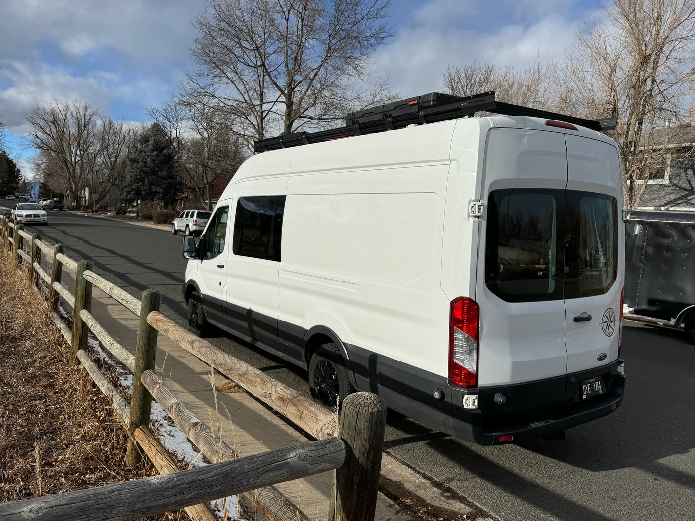 White Ford Transit camper van, perfect for an RV rental, parked on a suburban street.
