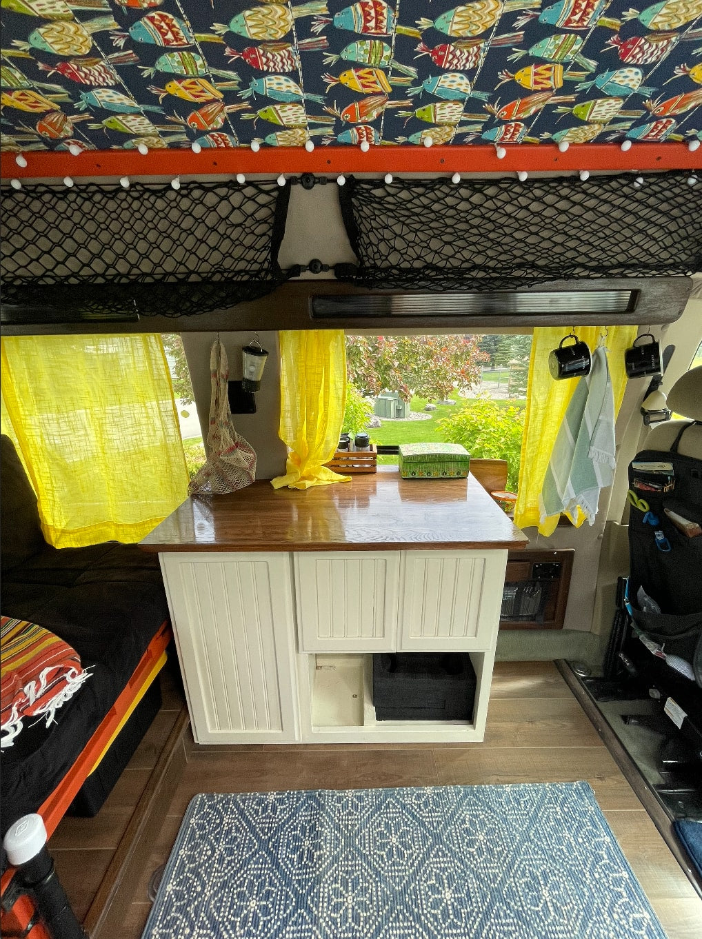 and bright yellow curtains for travel.|Unique RV rental interior with colorful bird-patterned ceiling