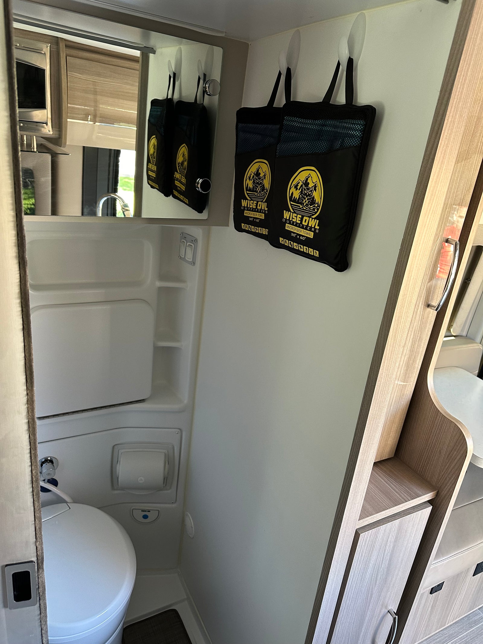 RV rental's compact interior features a bathroom with toilet and integrated shower, plus Wise Owl microfiber towels.