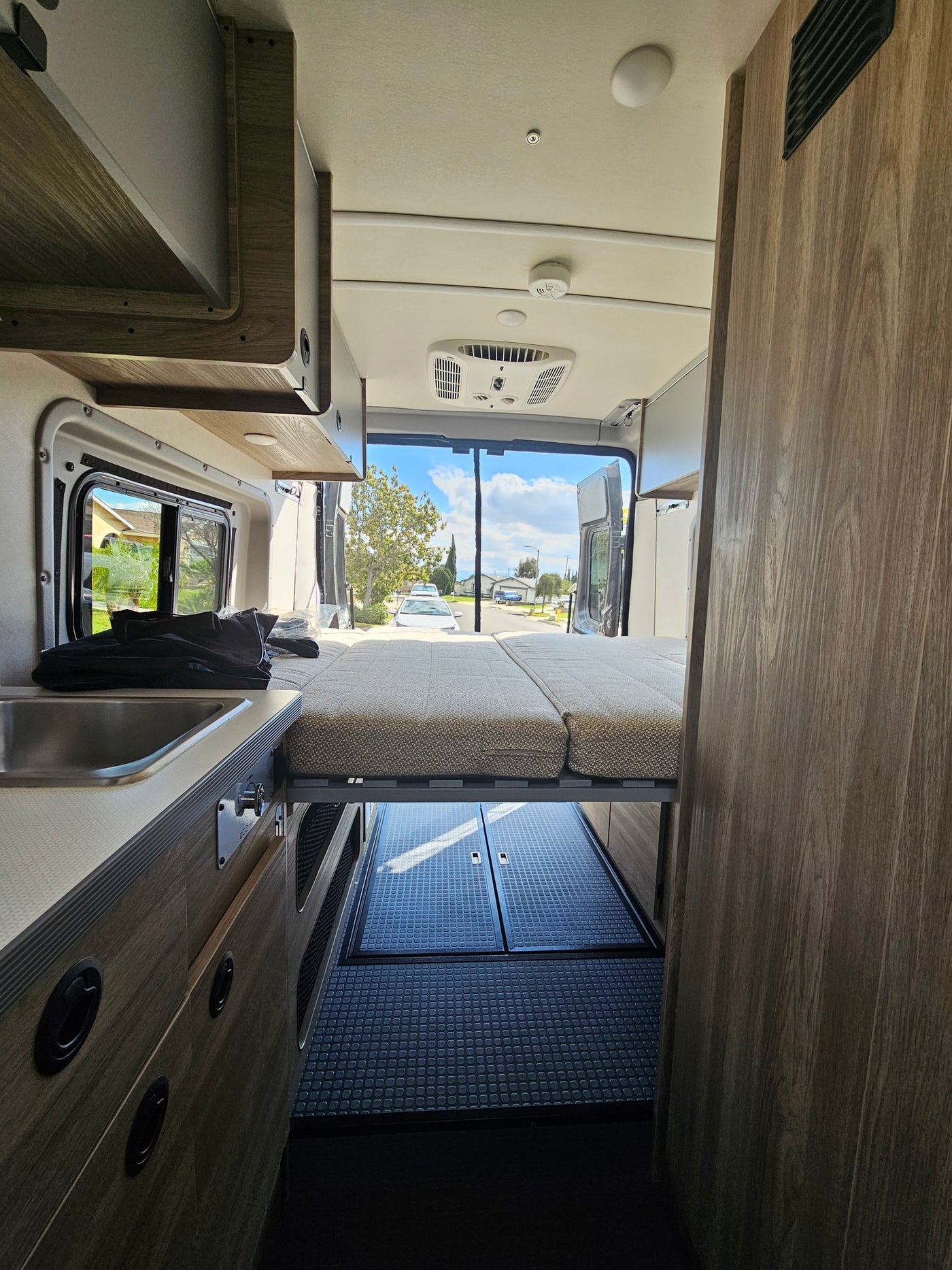 Modern RV rental interior: kitchen with sink, stove, microwave; living area with TV & storage. Compact & functional. — photo 2