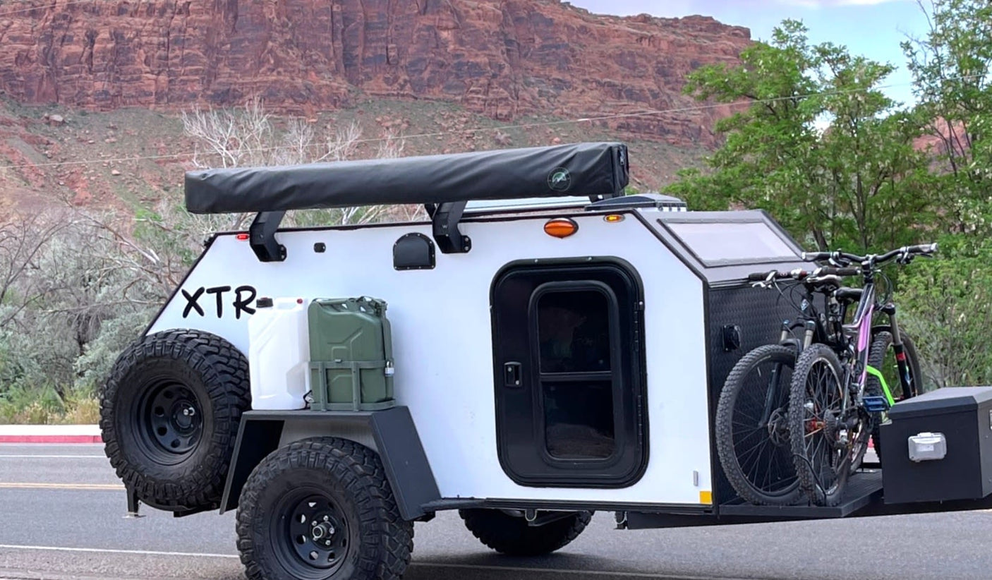 An XTR off-road camper trailer, perfect for RV rental adventures with mountain bikes & gear in mountainous terrain.