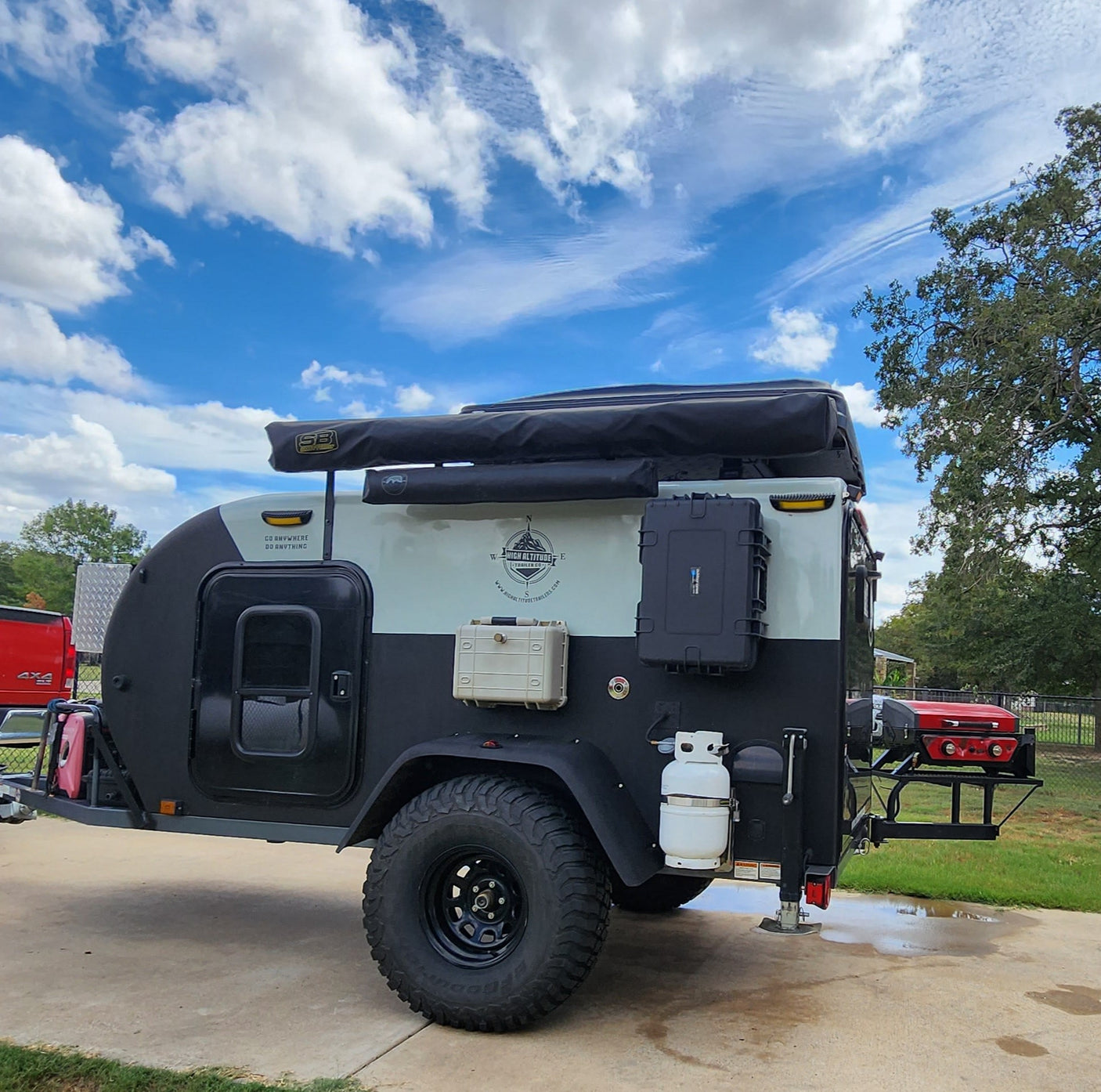 Teardrop camper RV rental: A black & light off-road trailer hitched to a red truck, ready for adventure.