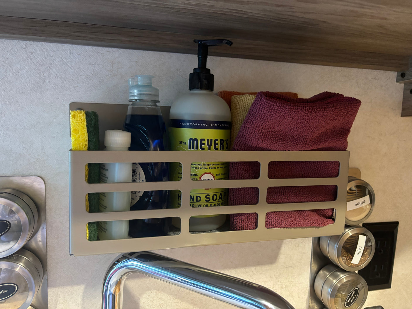 RV rental kitchen: Organized sink caddy holds Mrs. Meyer's soap, sponge, towels, & magnetic spices like sugar and garlic.