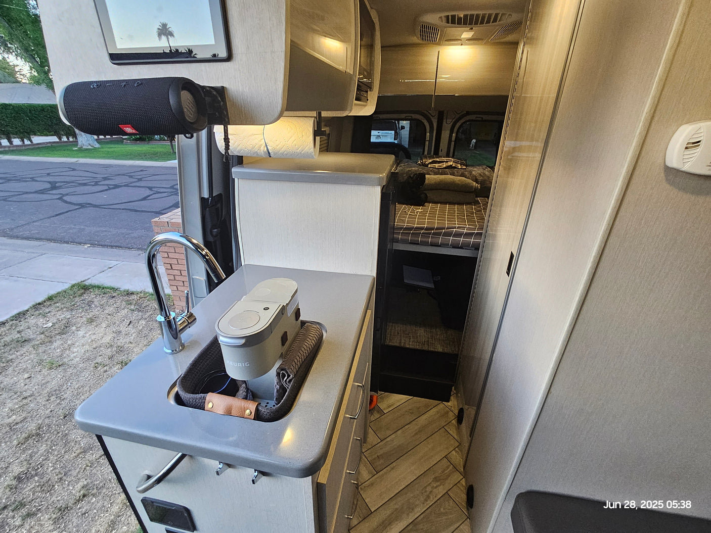 Explore this RV rental's clever interior: functional kitchen with Keurig & sink, leading to a cozy sleeping area.