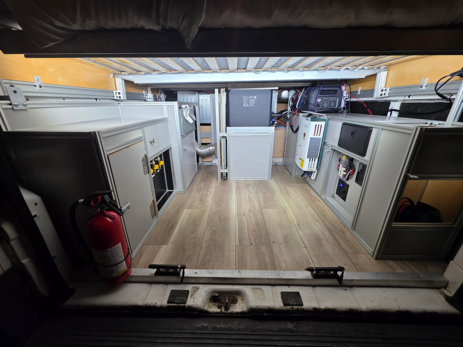 RV rental's custom van interior: aluminum cabinets, bed, power station, water heater, fire extinguisher for safe trips.