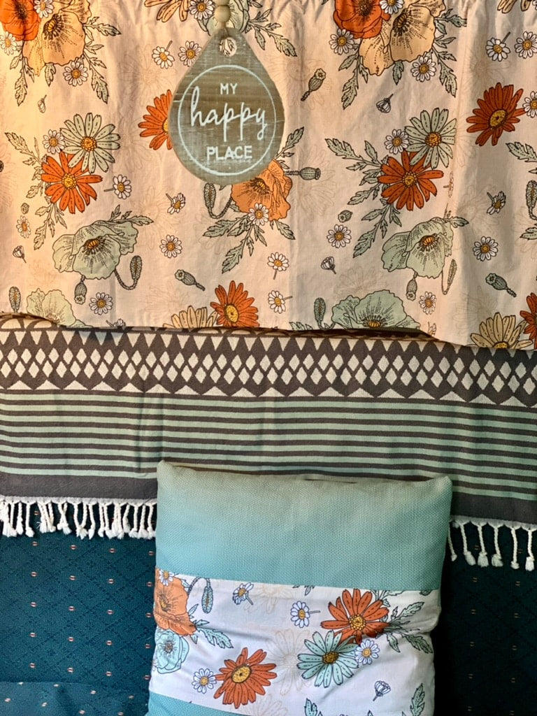 and floral-patterned seating.|Cozy retro RV rental interior: view of compact kitchen with stove