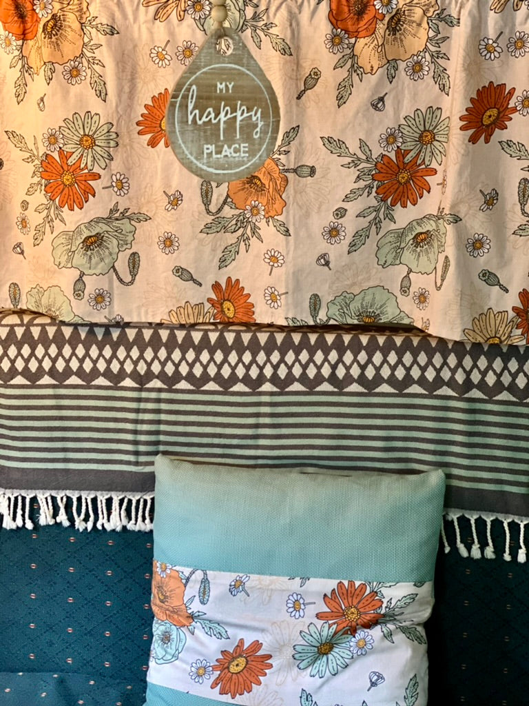 and floral-patterned seating.|Cozy retro RV rental interior: view of compact kitchen with stove