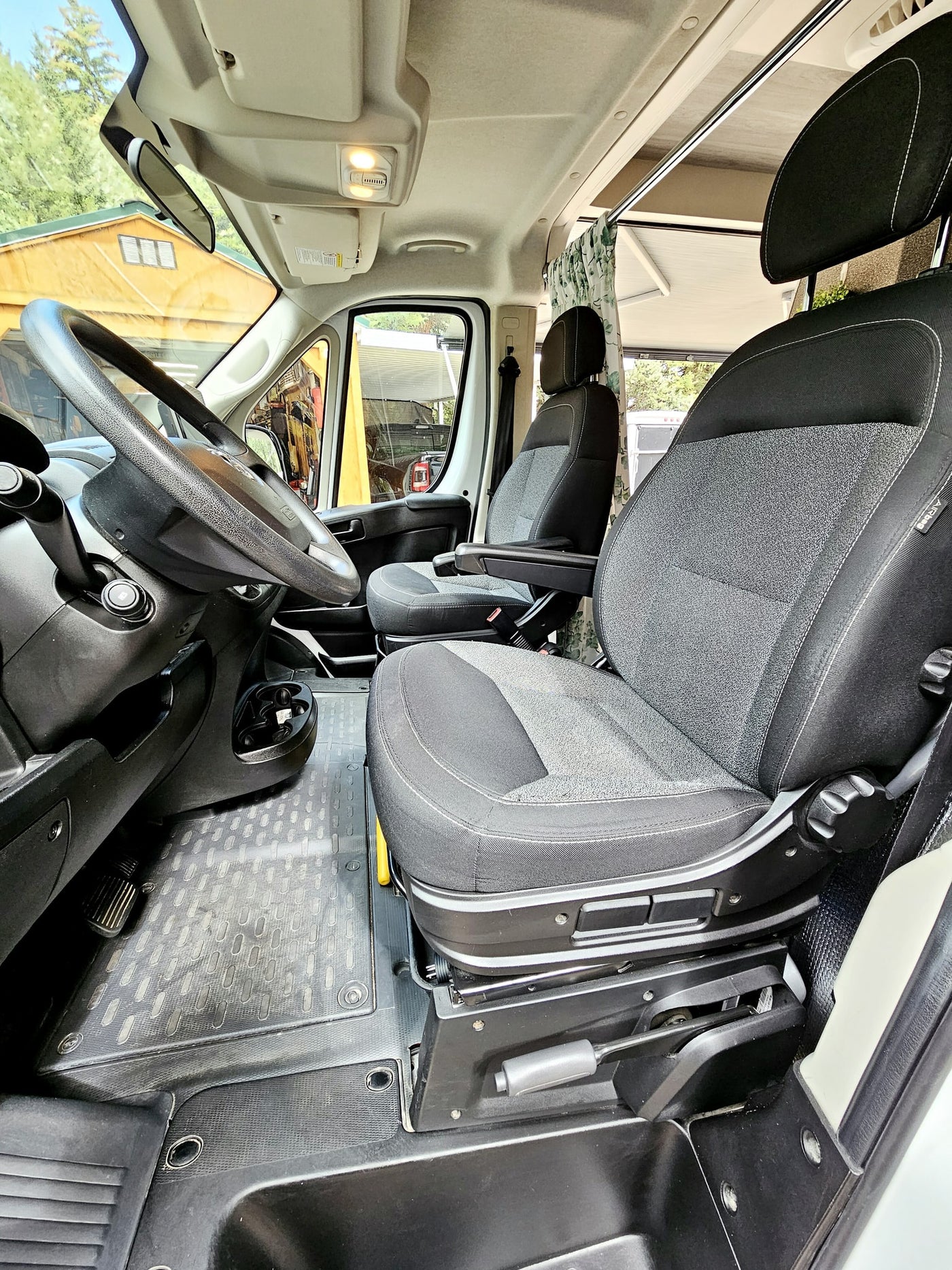 set against a lush forest.|Driver's view of an RV rental cockpit: Ram steering wheel — photo 2