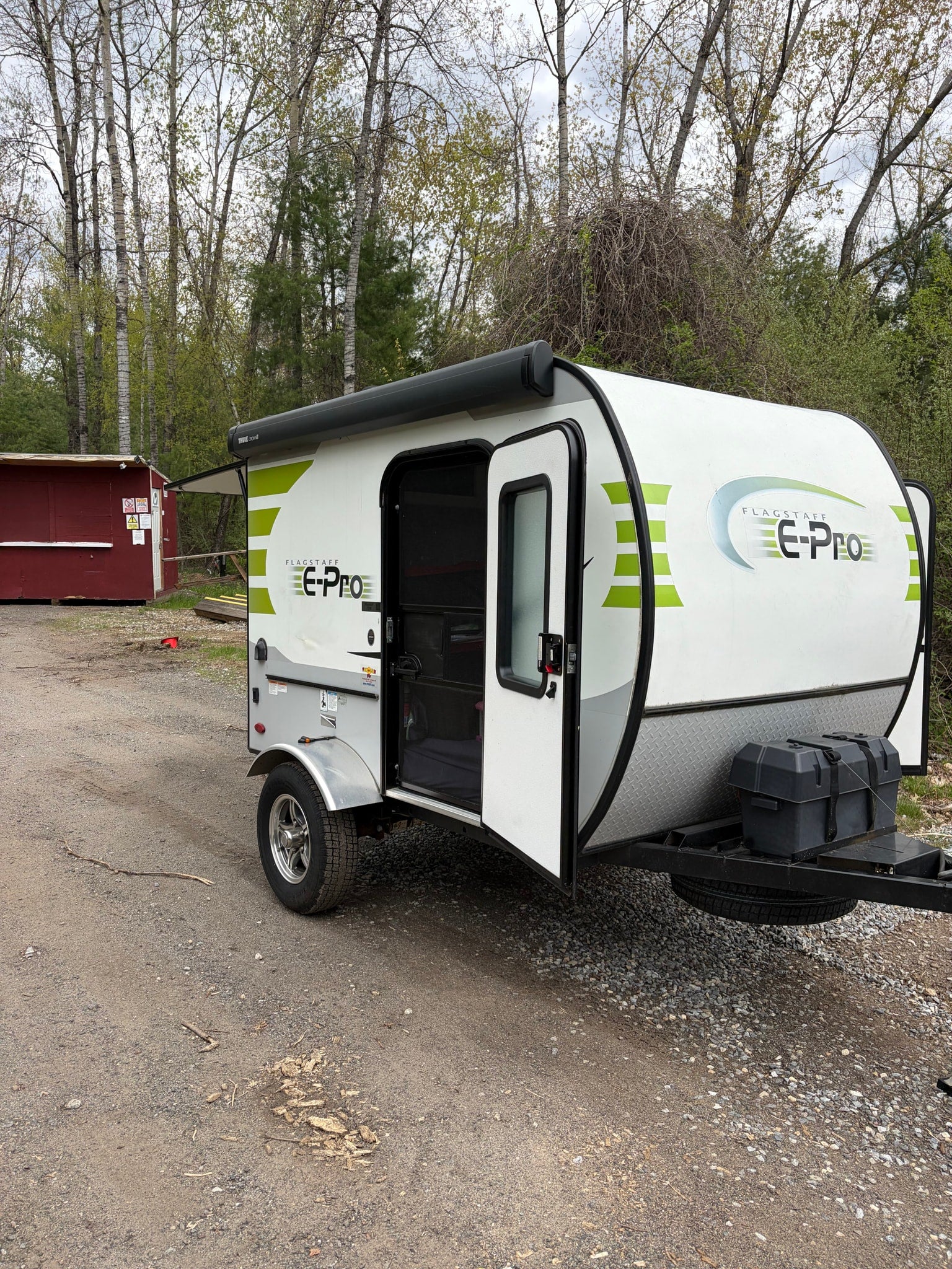 RV rental: A white and green Flagstaff E-Pro travel trailer with its door open, parked on a gravel lot.