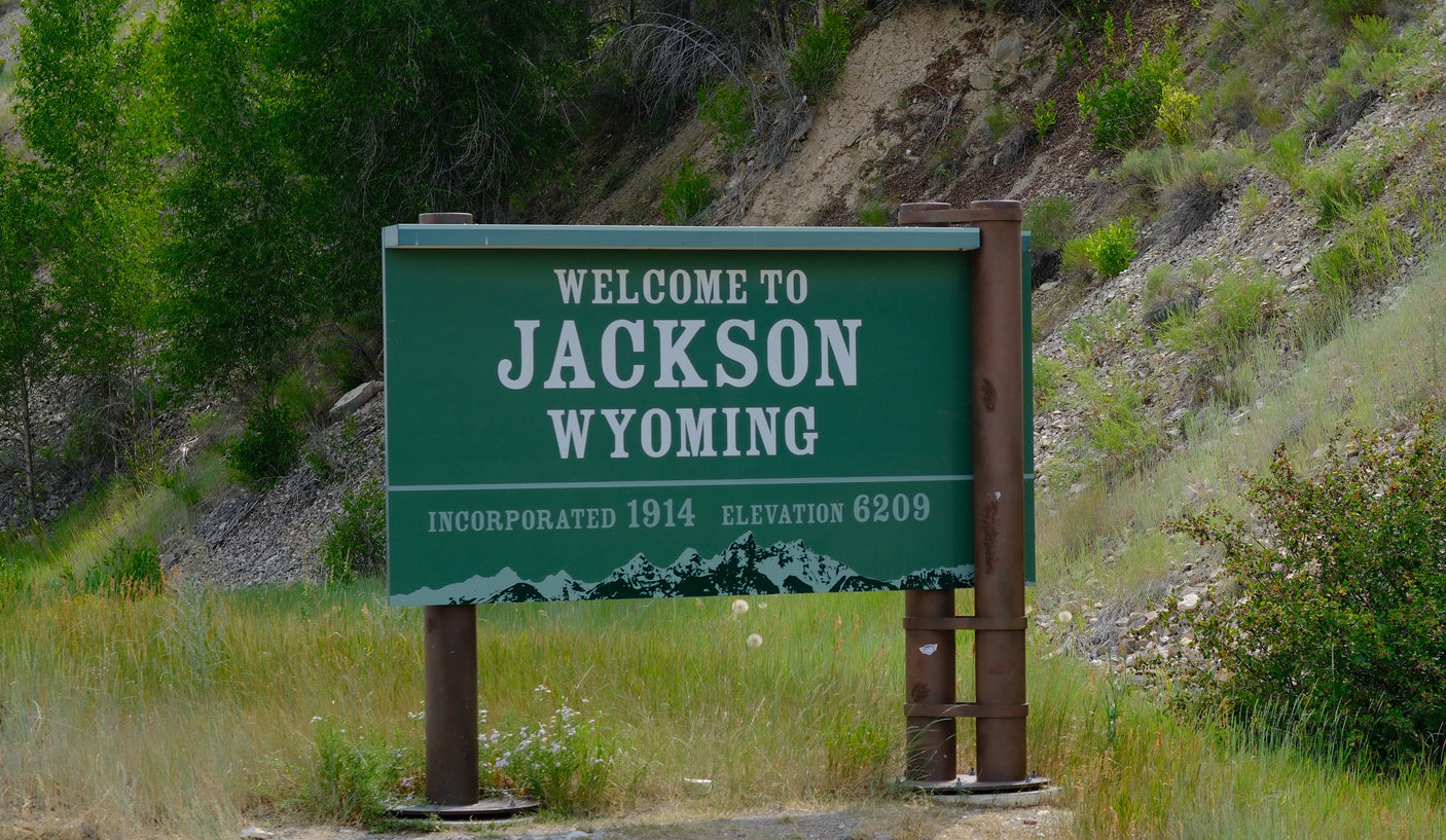 Green 'Welcome to Jackson Wyoming' sign, elevation 6209, with mountain graphic. Great for an RV rental road trip.
