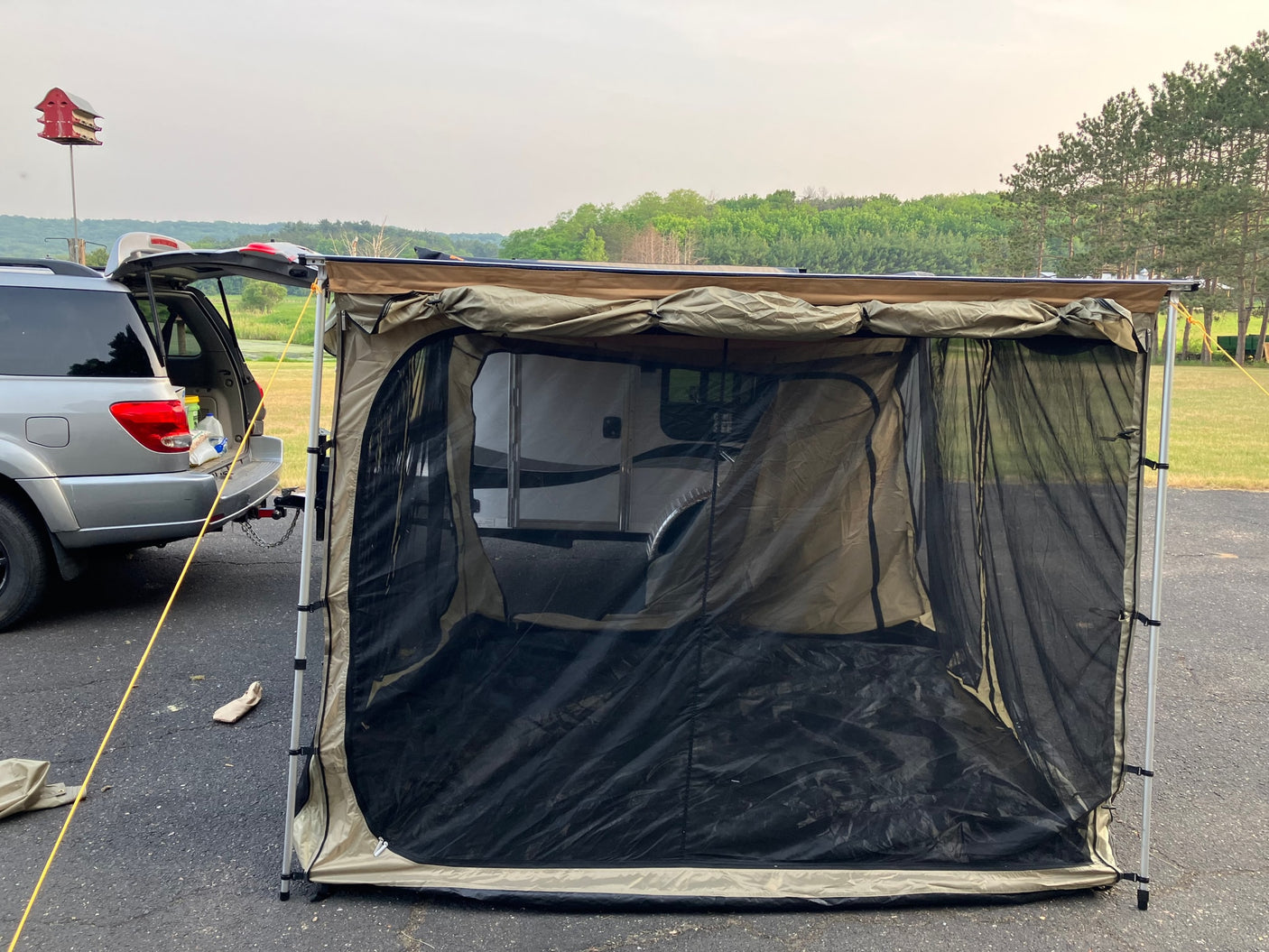 RV rental camp: SUV with awning & screen room enclosing a camper, providing shaded outdoor space.