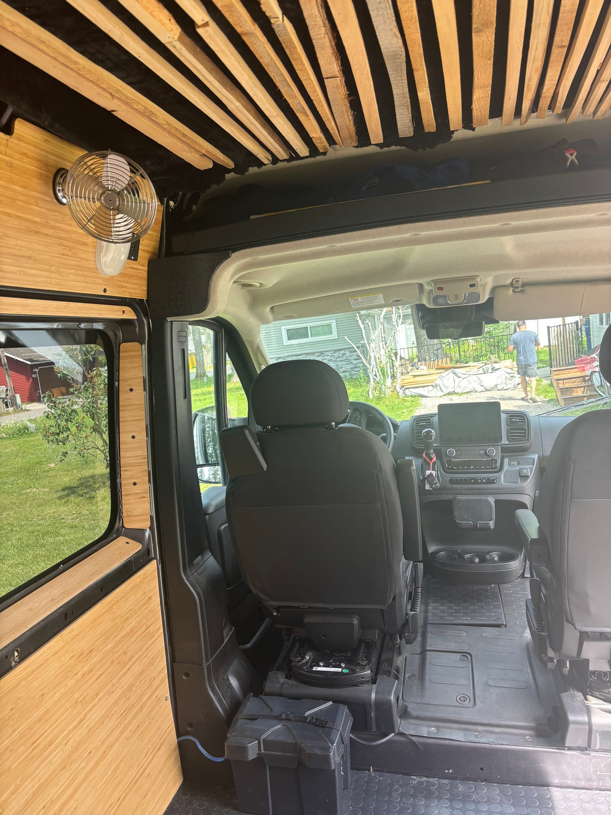 and a small table with snacks.|A dark gray RV rental camper van is parked on a gravel driveway — photo 7