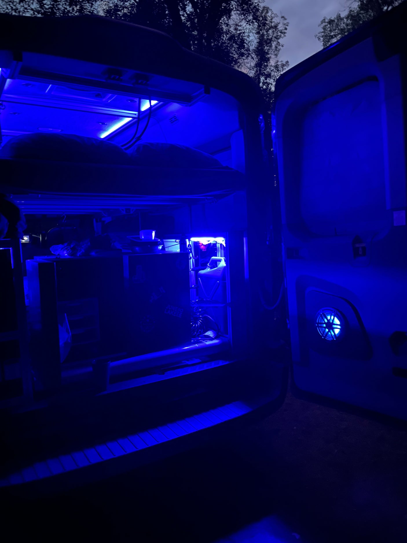 Blue-lit RV rental interior at night, showcasing a custom computer setup. Perfect for unique tech travel experiences.