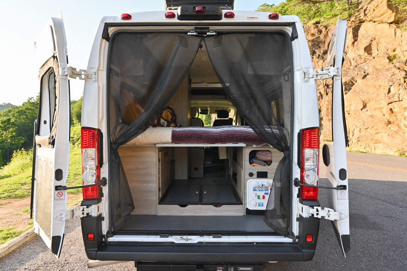 and two seats. Scenic mountain view with sun glare.|Scenic RV rental trip: A white camper van overlooks a stunning mountain vista where a couple relaxes on a blanket.|Cozy rv rental interior with swiveled front seats