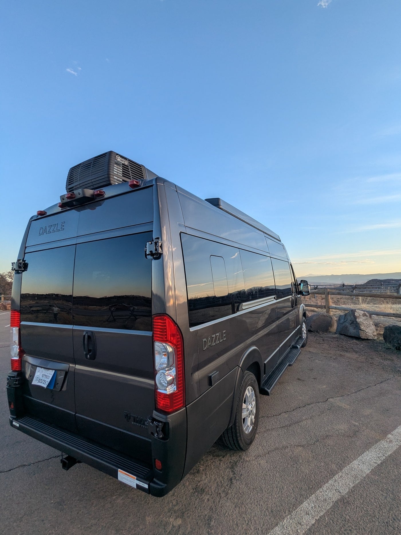 Dark grey Dazzle camper van RV rental parked at a scenic mountain overlook, reflecting the clear sky. — photo 17