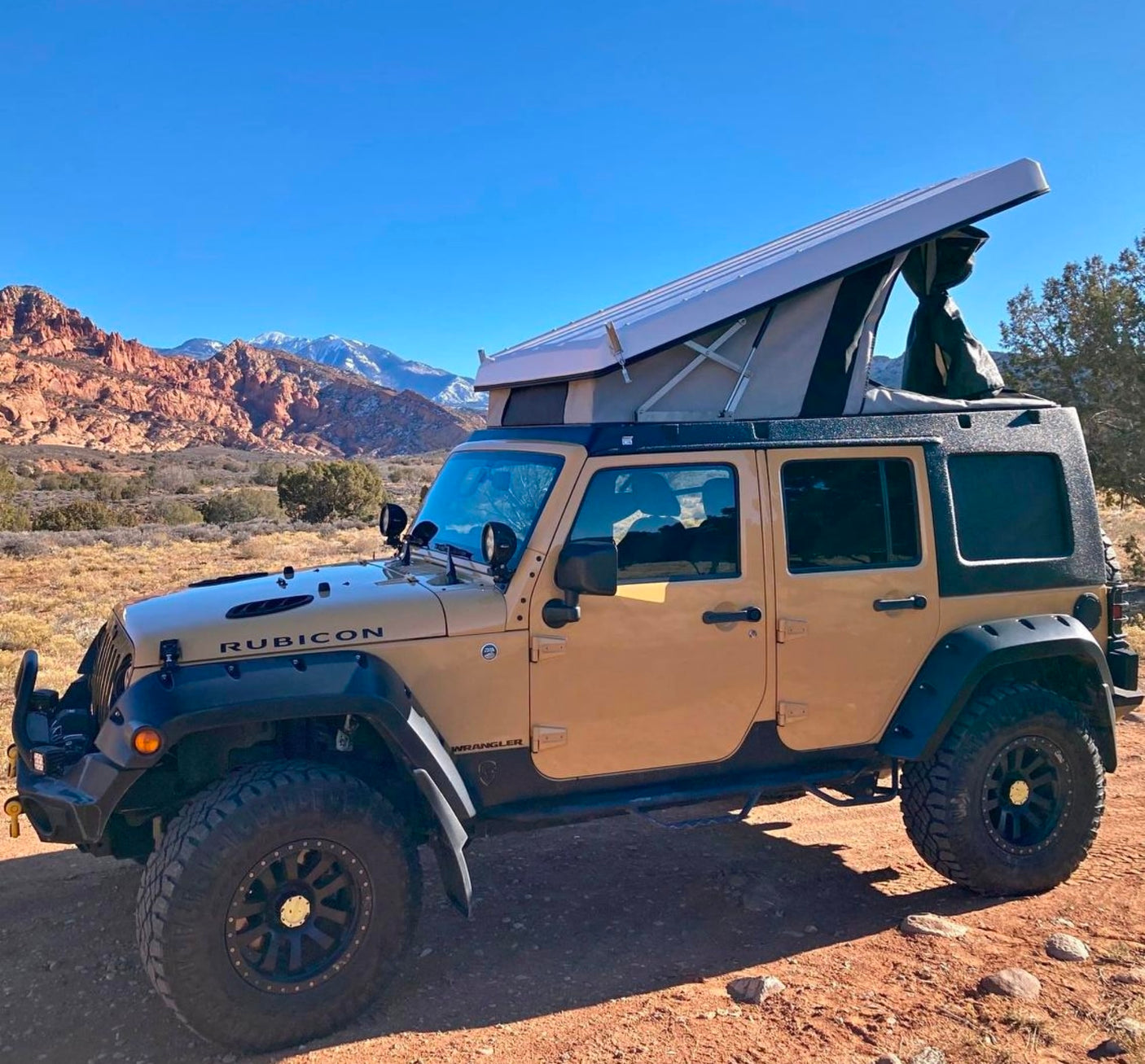 an ideal RV rental. Scenic mountains and autumn colors glow in golden light.|Tan Jeep Wrangler with a pop-top camper in a scenic mountain desert. An ideal RV rental for off-road adventure camping.|Experience night overlanding with this RV rental Jeep. Illuminated awning