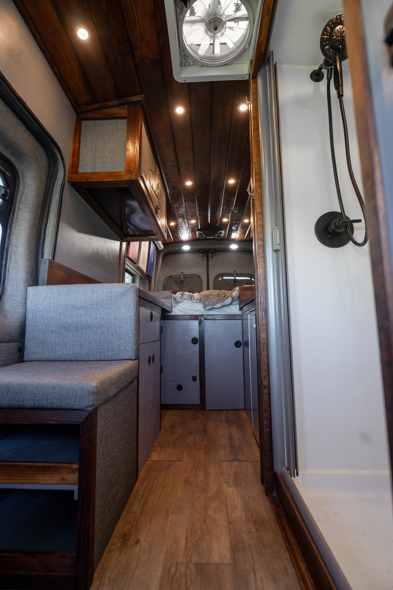 Step inside this cozy RV rental camper van. Features include a comfy bench, kitchen, bed, and built-in shower.
