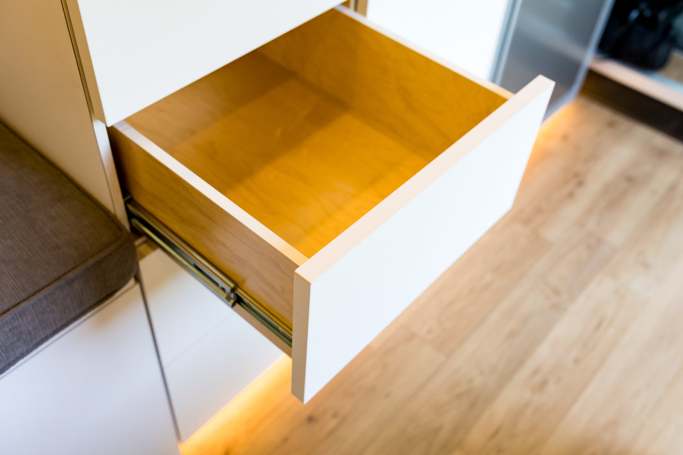 RV rental storage: An open wooden drawer with white trim and subtle under-cabinet lighting, showcasing compact interior space.