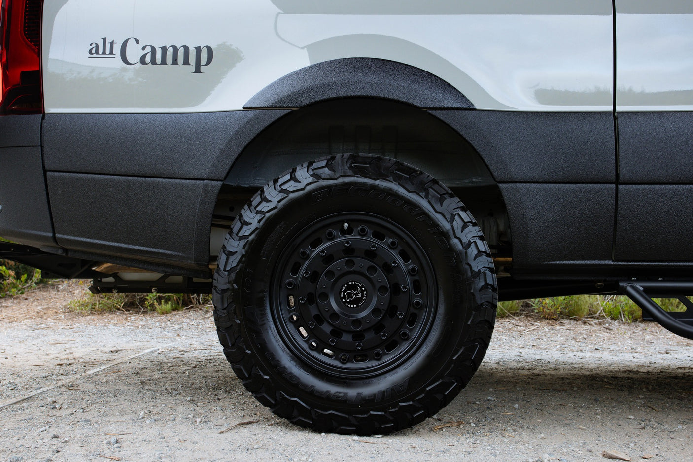 Alt Camp custom rv rental van with rugged off-road BFGoodrich tires & Black Rhino wheels on gravel.
