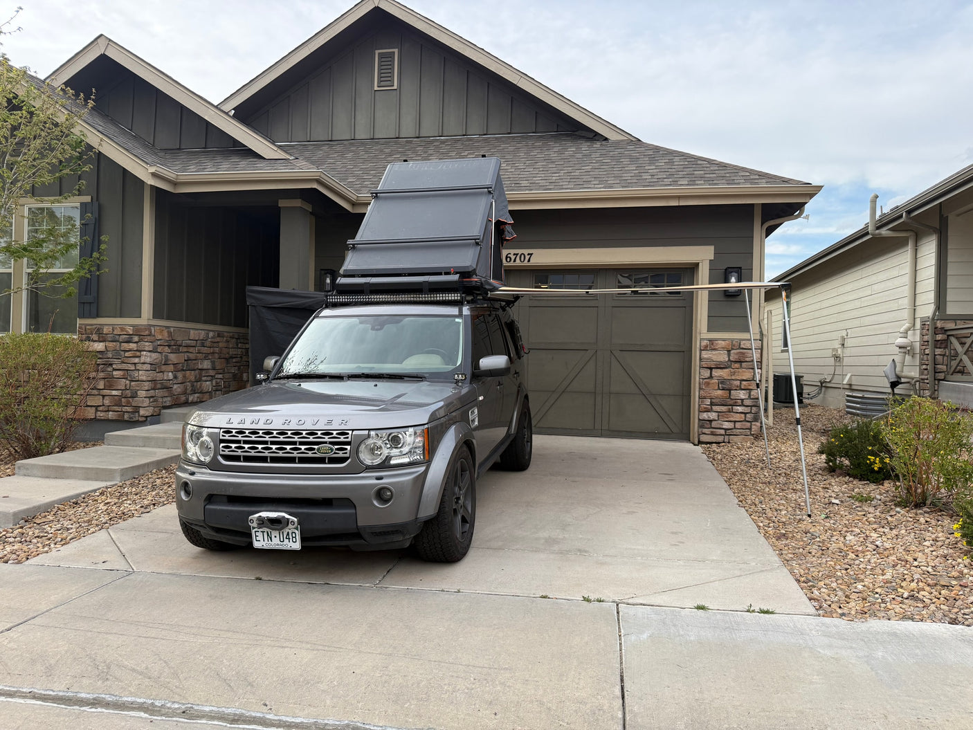 Gray Land Rover with deployed rooftop tent & awning. Great for an rv rental or overlanding trip!