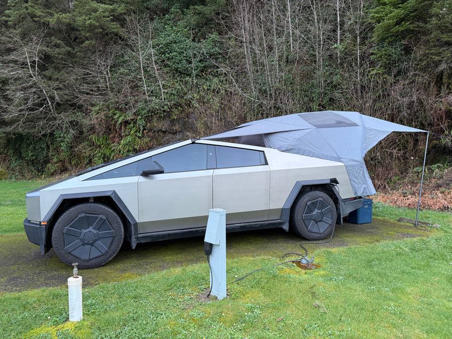 Electric Tesla Cybertruck, acting like an RV rental, set up with an attached tent & campsite hookups for glamping.