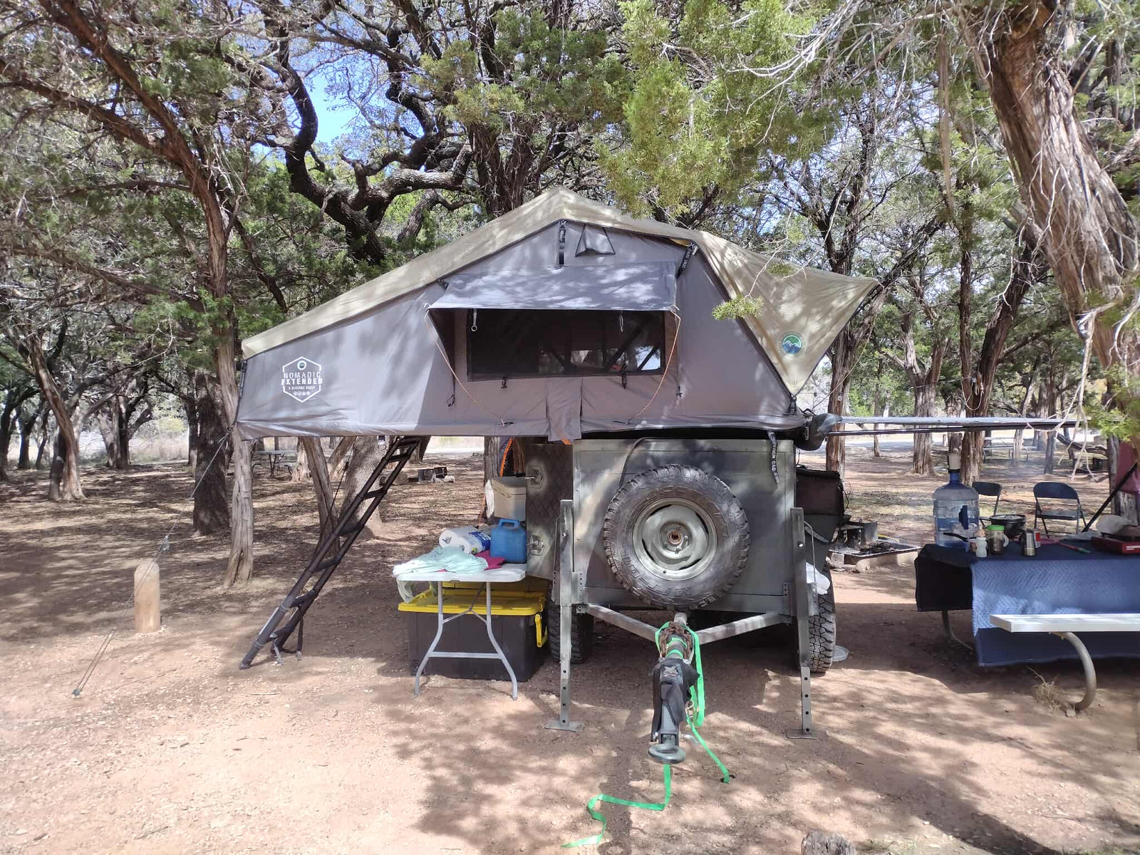 ready for camping trips.|Overlanding camping trailer with rooftop tent deployed in woods