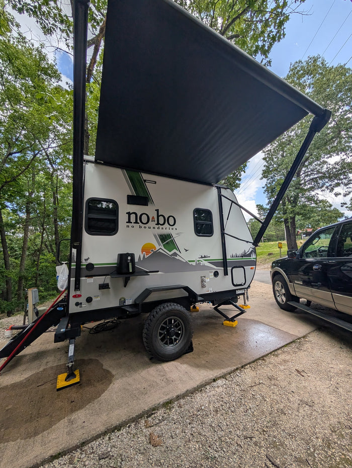 This No Boundaries travel trailer RV rental is parked at a campsite, ready for adventure with its extended awning.