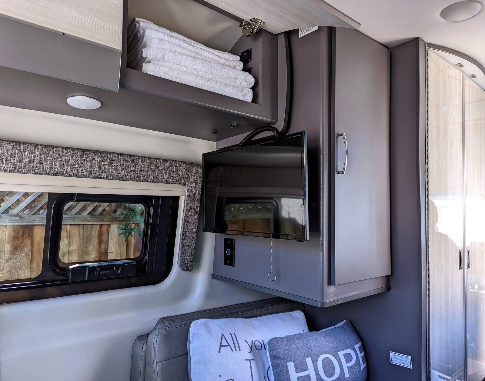 Cozy RV rental interior with TV, window, and storage for a comfortable journey.
