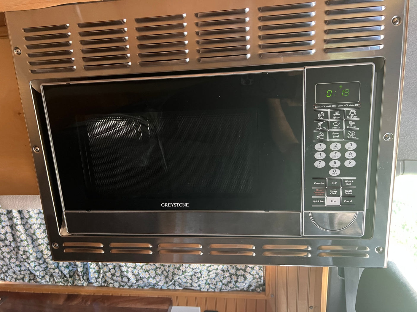 Stainless steel Greystone microwave with a digital display and control panel, ideal for an RV rental or camper kitchen.